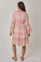 Woman wearing a pink dress with lace details on a white background