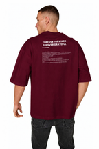 A man viewed from the back wearing a burgundy short-sleeve t-shirt with white printed text on the upper back, paired with dark gray jeans, against a plain white background.