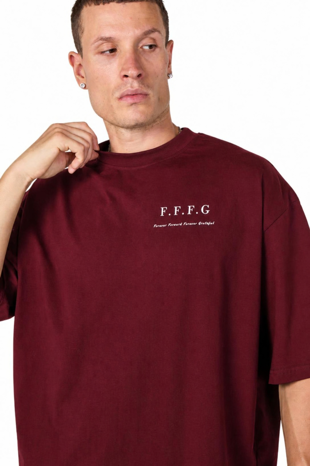 A man wearing an oversized maroon crewneck t-shirt with 'F.F.