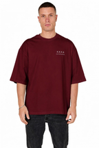 A man wearing an oversized maroon t-shirt with a small white 'F.F.