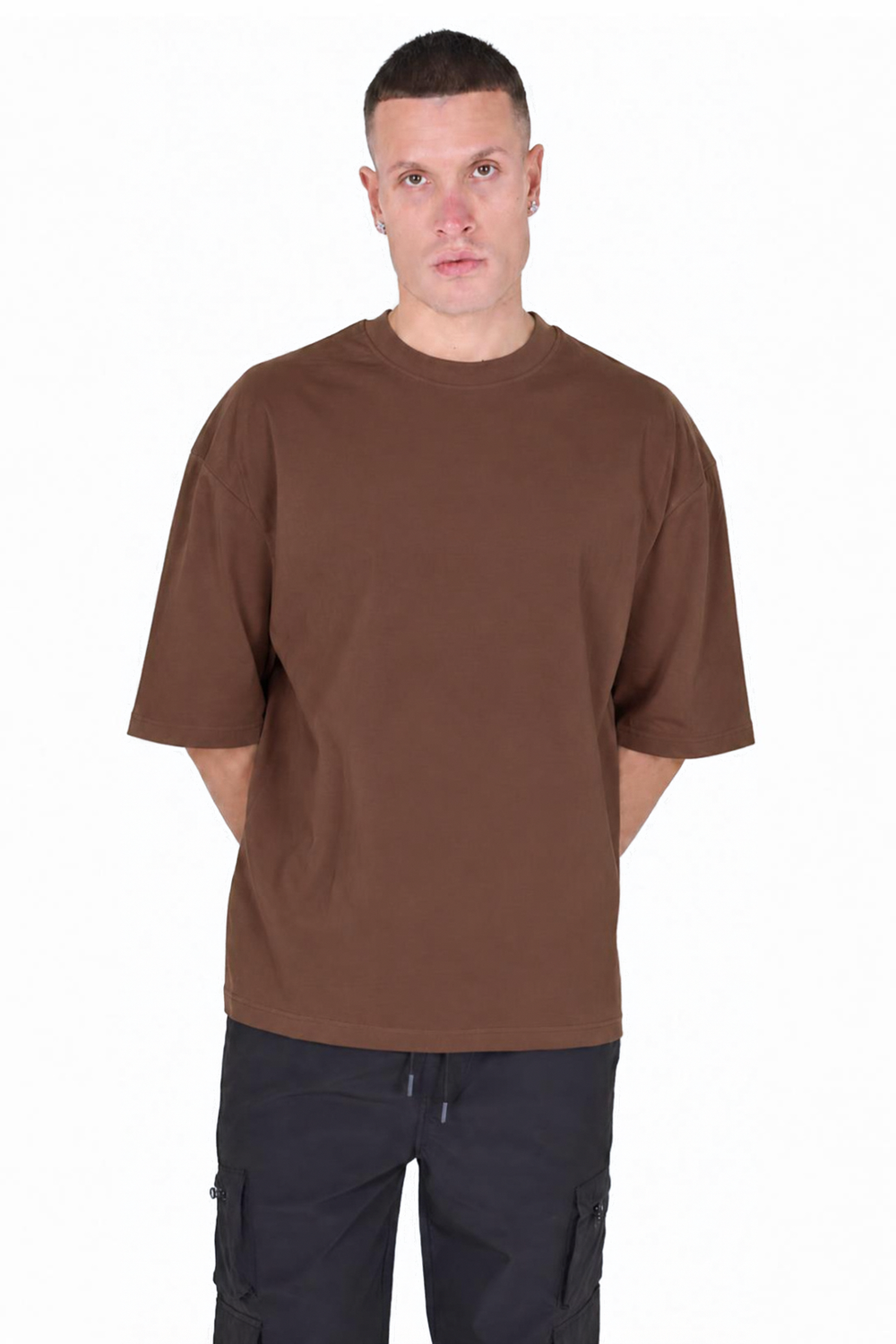 A man wearing a plain brown short-sleeve crewneck t-shirt and dark cargo pants, standing against a solid white background. Main image