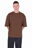 A man wearing a plain brown short-sleeve crewneck t-shirt and dark cargo pants, standing against a solid white background.