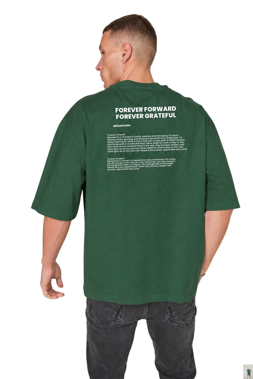 A man viewed from the back wearing an oversized dark green t-shirt with white printed text on the back, paired with dark gray jeans, against a plain white background.