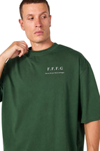 A man wearing an oversized dark green t-shirt with 'F.F.