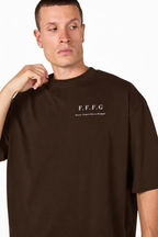 A man wearing an oversized dark brown t-shirt with 'F.F.