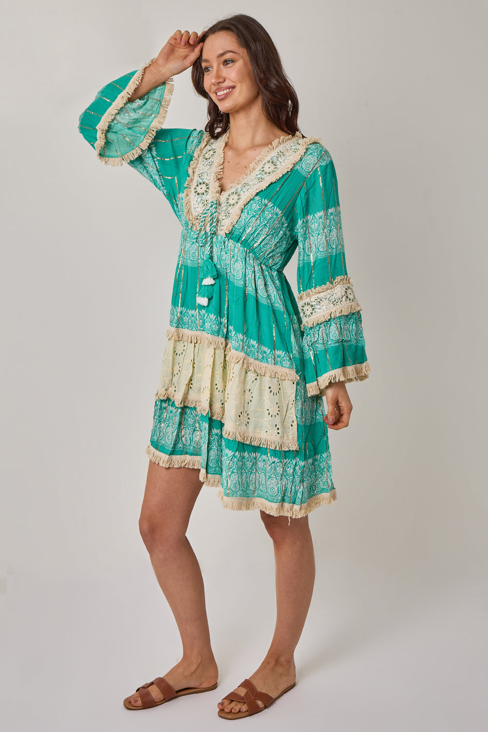 Woman wearing a green and white patterned dress on a plain background