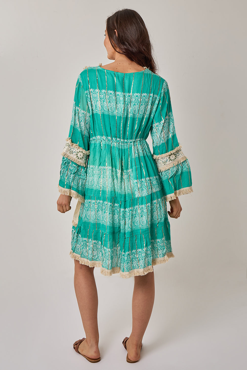 Woman wearing a green patterned dress with lace details on a plain background