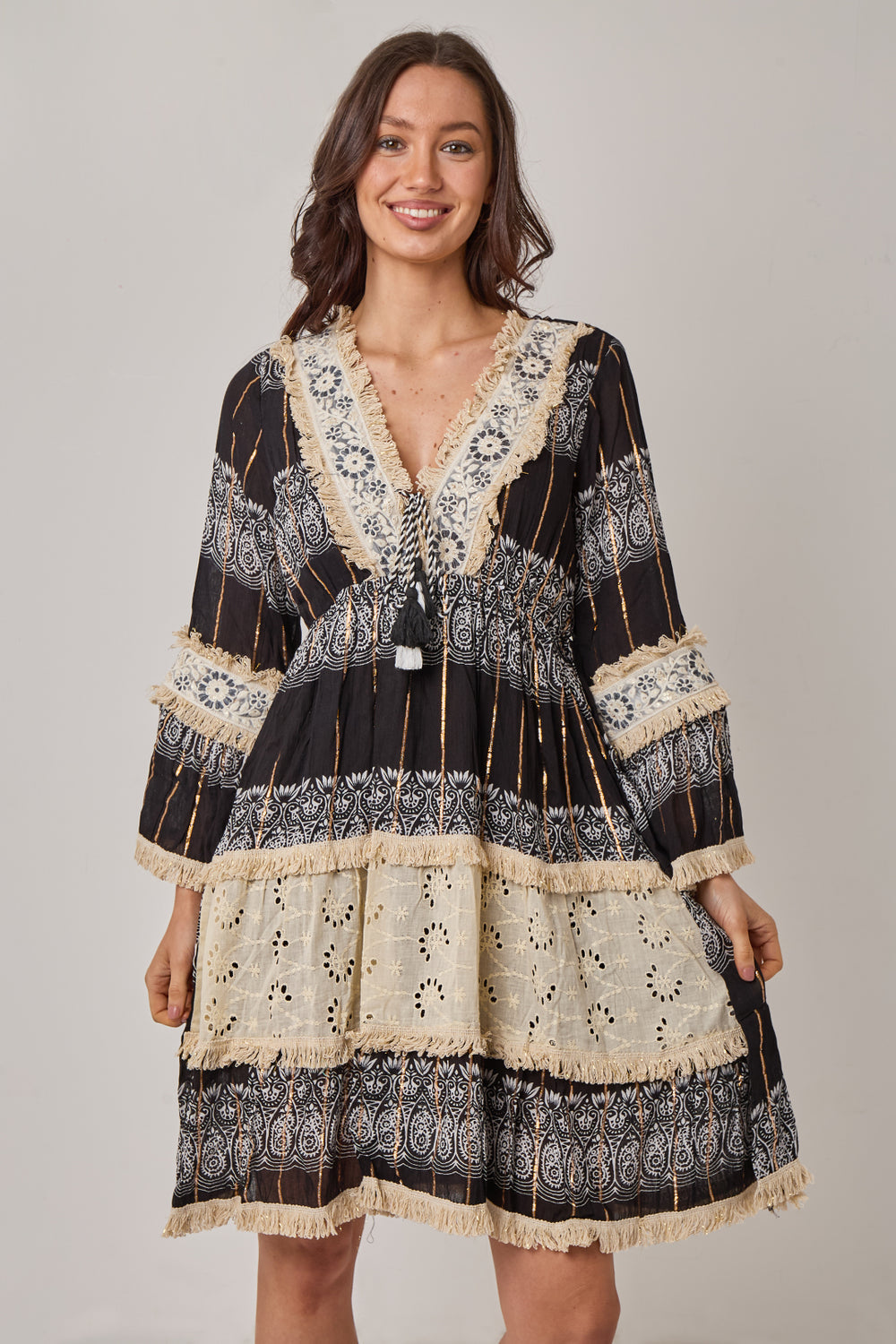 Woman wearing a black and beige patterned dress on a gray background