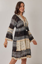 Woman wearing a black and white patterned dress with long sleeves on a plain background