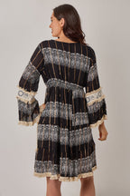 Woman wearing a black and white patterned dress with long sleeves on a plain background