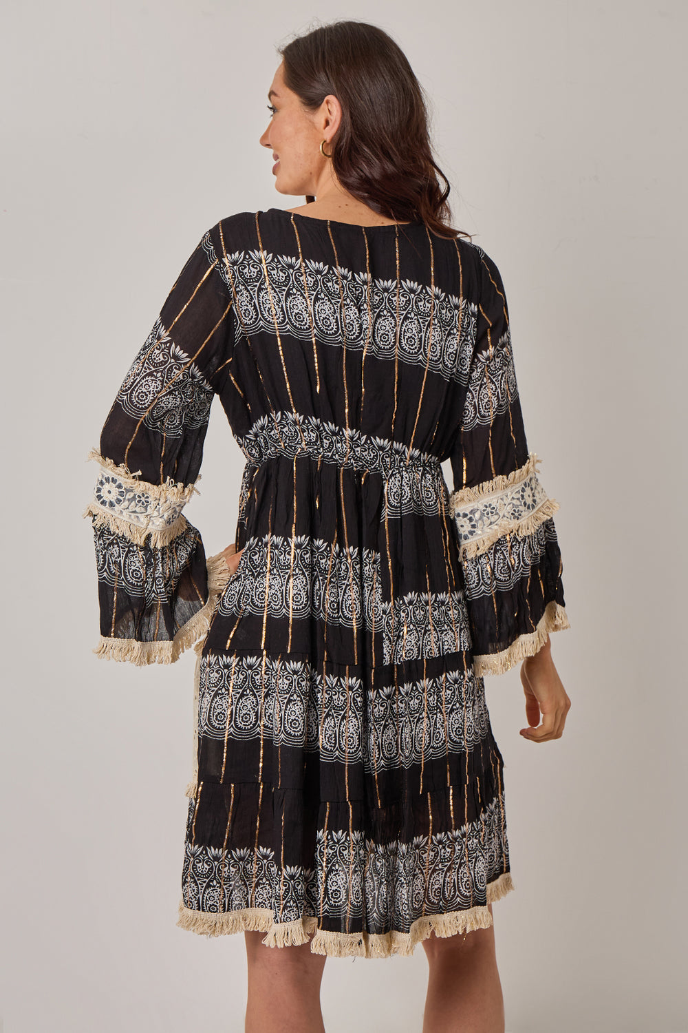Woman wearing a black and white patterned dress with long sleeves on a plain background