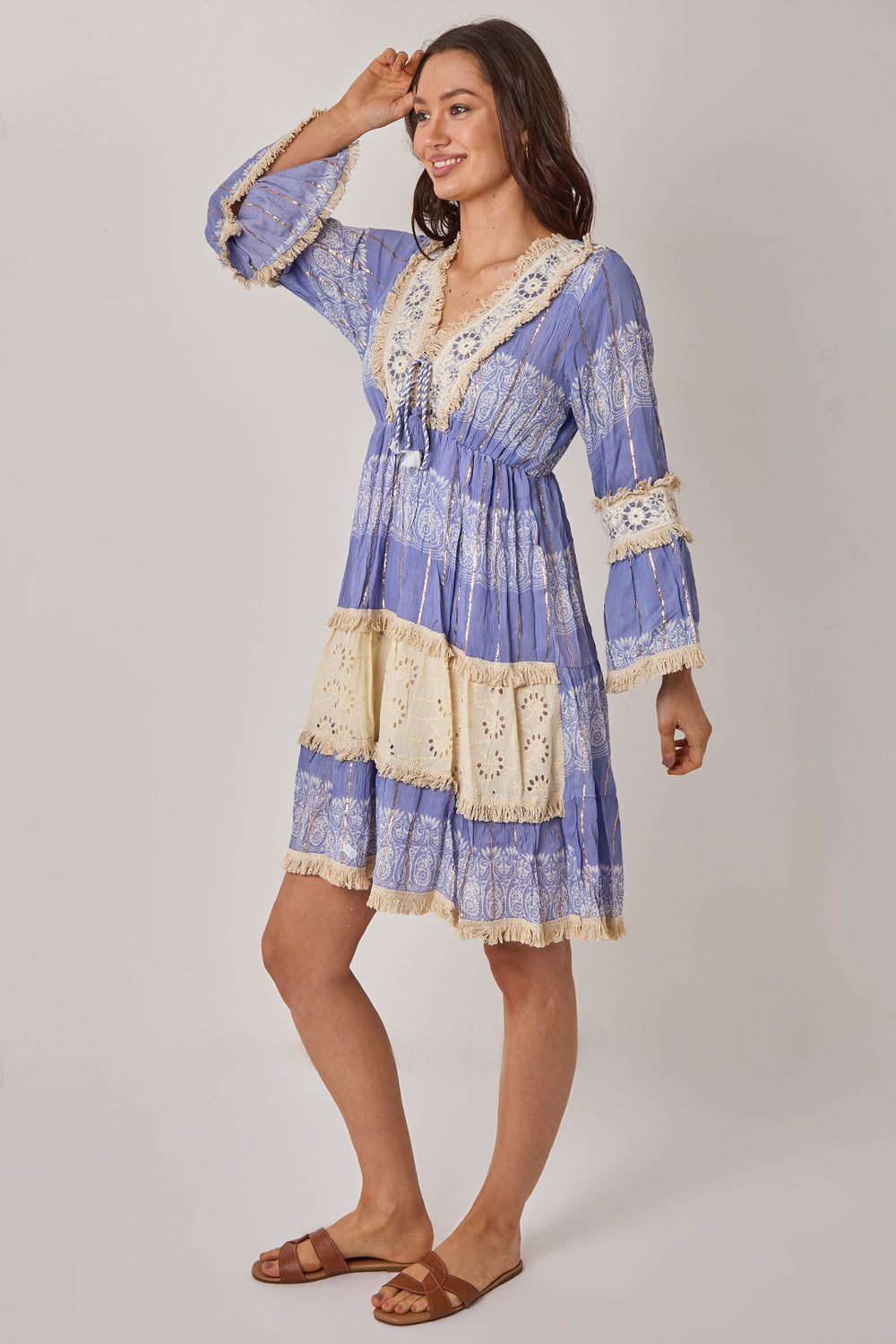 Woman wearing a blue and white patterned dress with lace details on a plain background