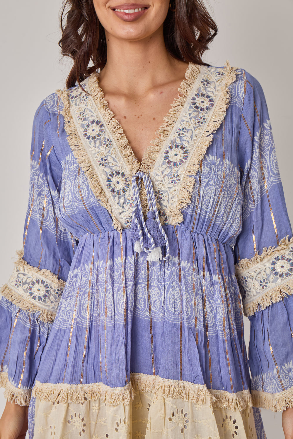 Woman wearing a blue and beige patterned dress with lace details.