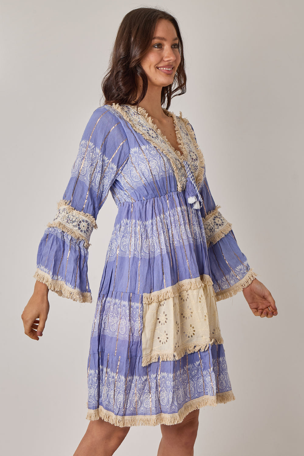 Woman wearing a blue and beige patterned dress on a plain background