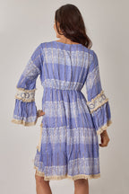 Woman wearing a blue patterned dress with long sleeves on a plain background