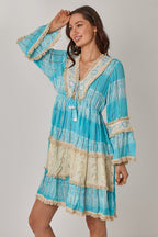 Woman wearing a blue and beige dress with lace details on a gray background