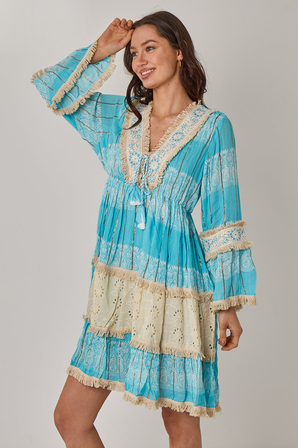 Woman wearing a blue and beige dress with lace details on a gray background