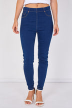 A model wearing dark blue high-waisted skinny jeans with rolled cuffs and white heeled sandals, shown from the waist down against a white studio background.