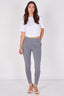 A woman modeling a pair of light gray skinny jeans, paired with a white cropped t-shirt and white heeled sandals, standing against a plain white studio background.