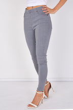A model wearing gray skinny jeans and white strappy high-heeled sandals, shown from the waist down against a plain white studio background.