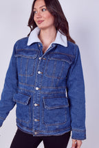 A woman wearing a blue denim jacket with a white sherpa collar, photographed against a light gray studio background.