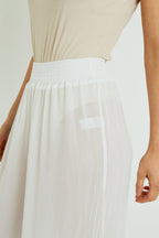 White skirt worn by a person on a plain background