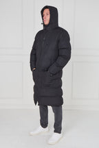 Person wearing a black hooded coat against a white background