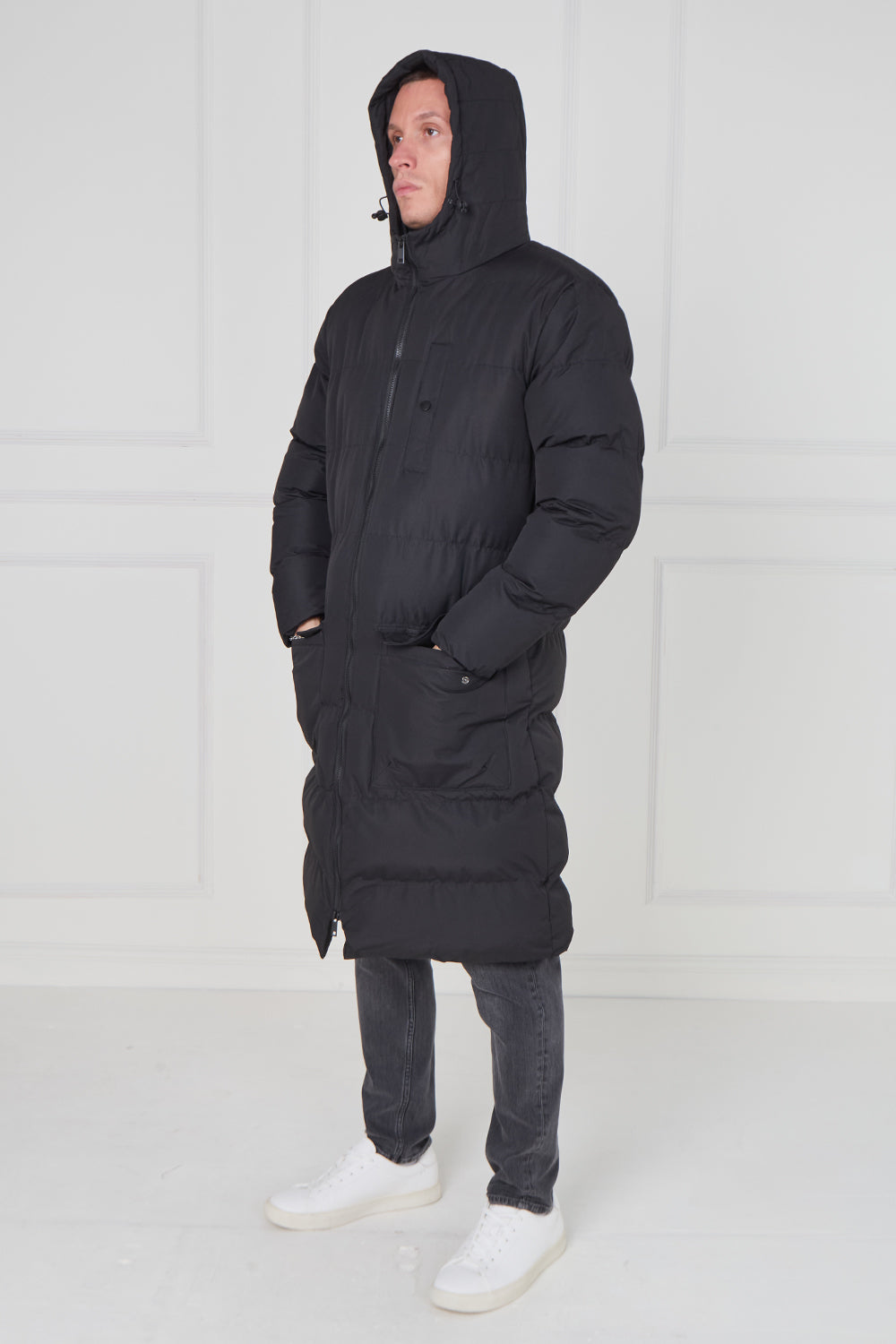 Person wearing a black hooded coat against a white background