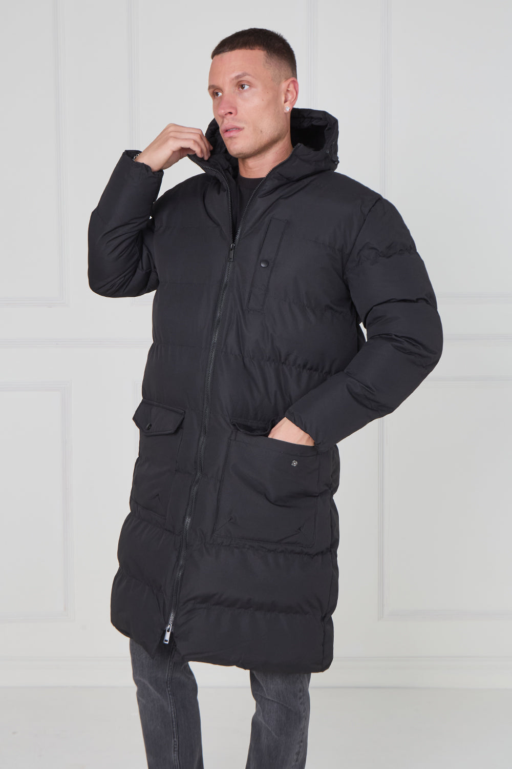 Man wearing a black puffer coat against a white background