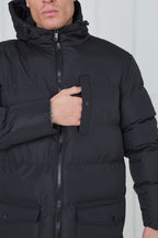 Black winter coat with a hood worn by a person against a white background
