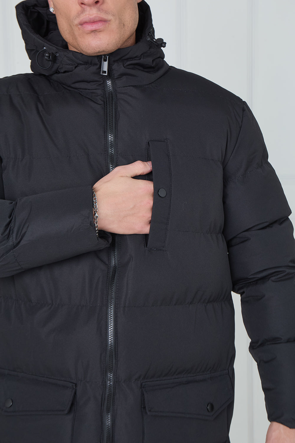 Black winter coat with a hood worn by a person against a white background