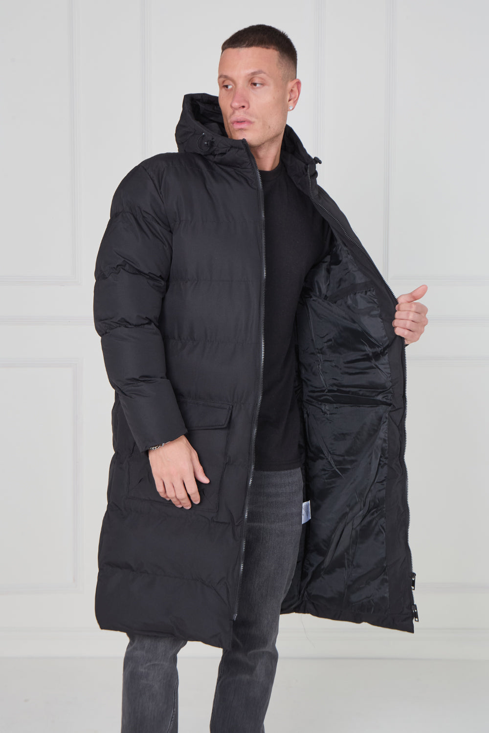 Man wearing a black puffer coat against a white background