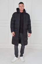 Man wearing a long black puffer coat against a white background