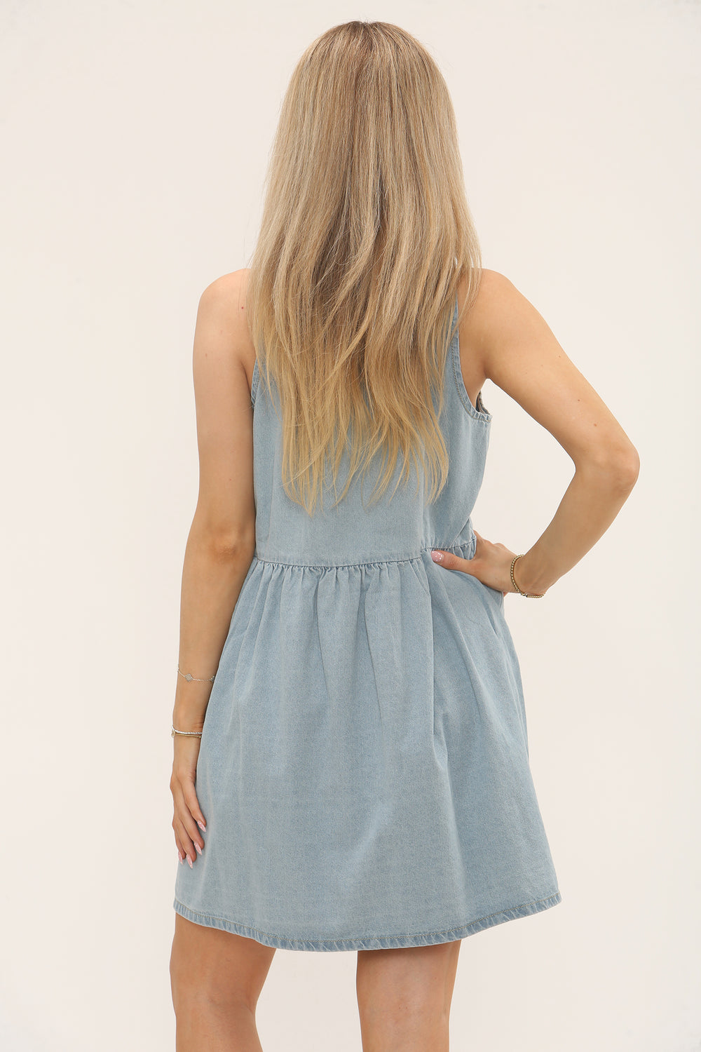 Woman wearing a light blue sleeveless denim smock dress made from 100% cotton, relaxed fit, casual summer outfit, UK size 8