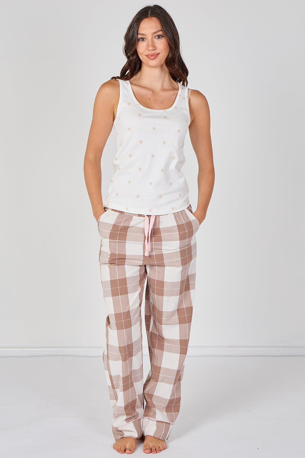 Woman wearing a white tank top and plaid pajama pants on a white background