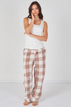 Woman wearing a white tank top and plaid pajama pants on a white background