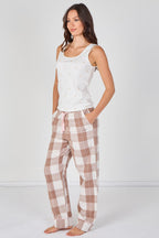 Woman wearing a white sleeveless top and plaid pants on a white background