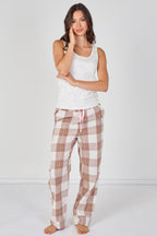 Woman wearing a white tank top and plaid pajama pants on a white background