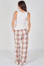 Woman wearing a sleeveless top and plaid pants on a white background