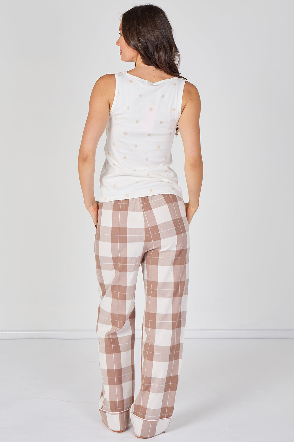 Woman wearing a sleeveless top and plaid pants on a white background
