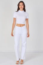 Woman wearing a white crop top and white pants on a plain background