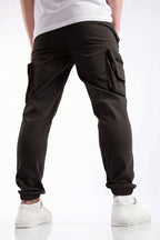 Black cargo jogger pants with side flap pockets and elastic cuffs, shown on a model from the back wearing a white t-shirt and white sneakers.